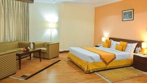 A hotel room with a bed, two armchairs, a coffee table, and a nightstand with lamps. - Summit Residency Airport Hotel (Kathmandu)