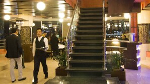 A modern hotel lobby with a central staircase, a reception desk, and a seating area. - Summit Residency Airport Hotel (Kathmandu)