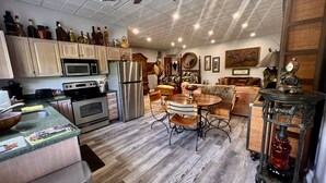 Una cocina moderna con electrodomésticos de acero inoxidable, un comedor con mesa y sillas de madera, y una sala de estar con sofá y elementos decorativos.