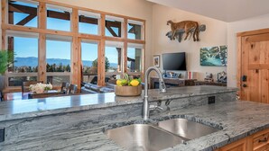 A kitchen with a large window, a sink, and a mounted animal sculpture. - 4 king beds w/ ensuites | Double the Living Space! (Bigfork)