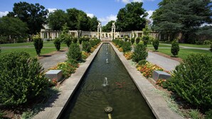 A formal garden with a central water feature, symmetrical landscaping, and classical statues.