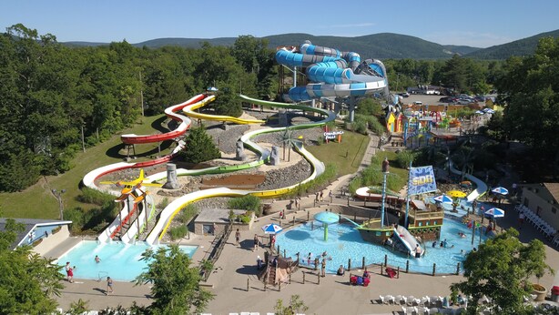 A water park with multiple slides and pools, surrounded by trees and hills.