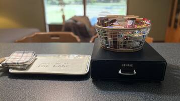 Eine Küchenarbeitsplatte mit einer Keurig-Kaffeemaschine, einer Snackkorb und einer Unterlage mit dem Aufdruck 'Meet Me at the Lake'.