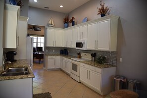 A kitchen with white cabinets, a granite countertop, a microwave, and a sink. - Newly remodeled coach home & golf membership in Vasari Country Club. (Bonita Springs)