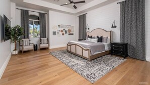 Une chambre spacieuse avec un grand lit, un ventilateur de plafond et une vue sur l’extérieur grâce à une porte coulissante.