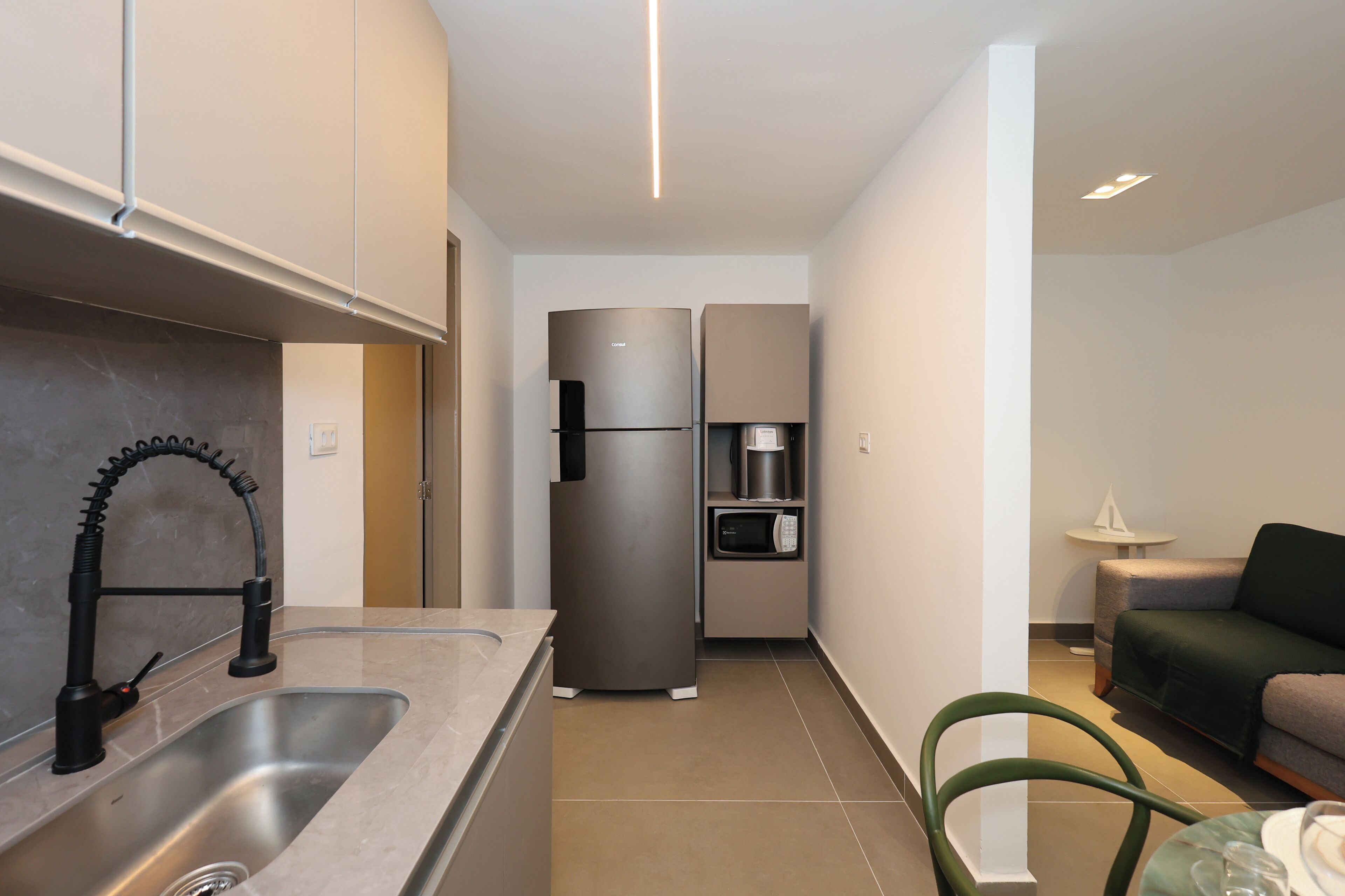 Una cocina moderna con un lavamanos de acero inoxidable, un microondas empotrado y un refrigerador.