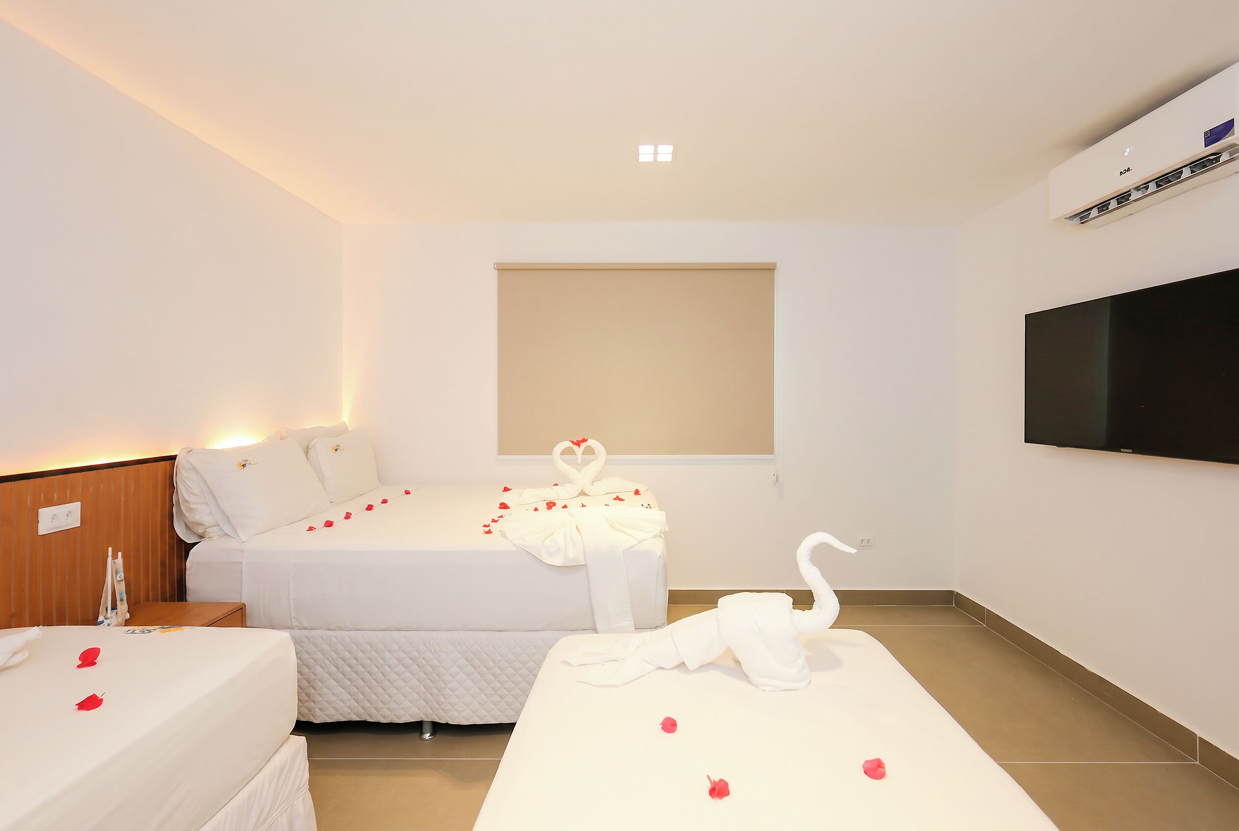 A hotel room with two beds, a TV, and a window.