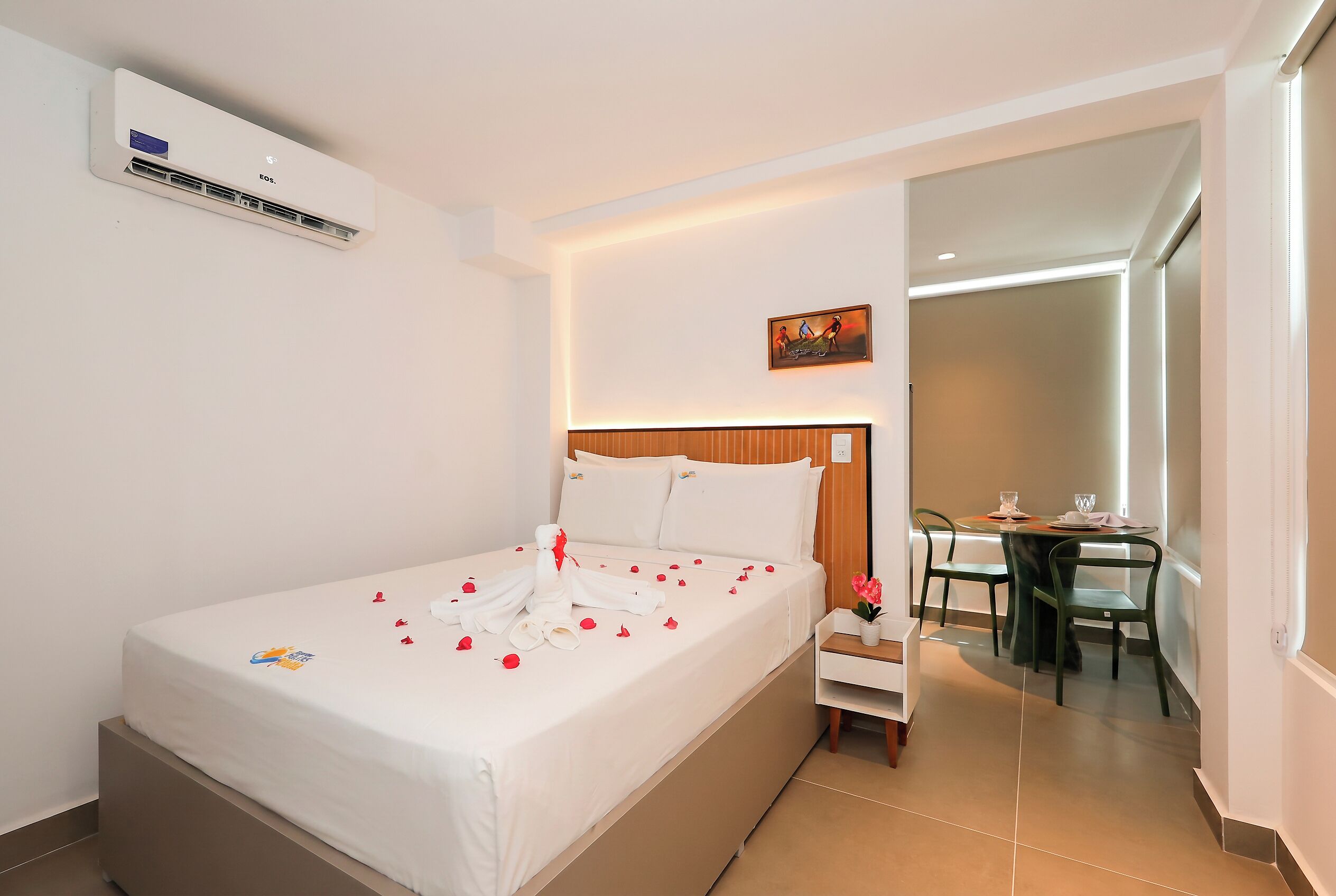 A hotel room with a bed, bedside table, and a small desk with chairs.