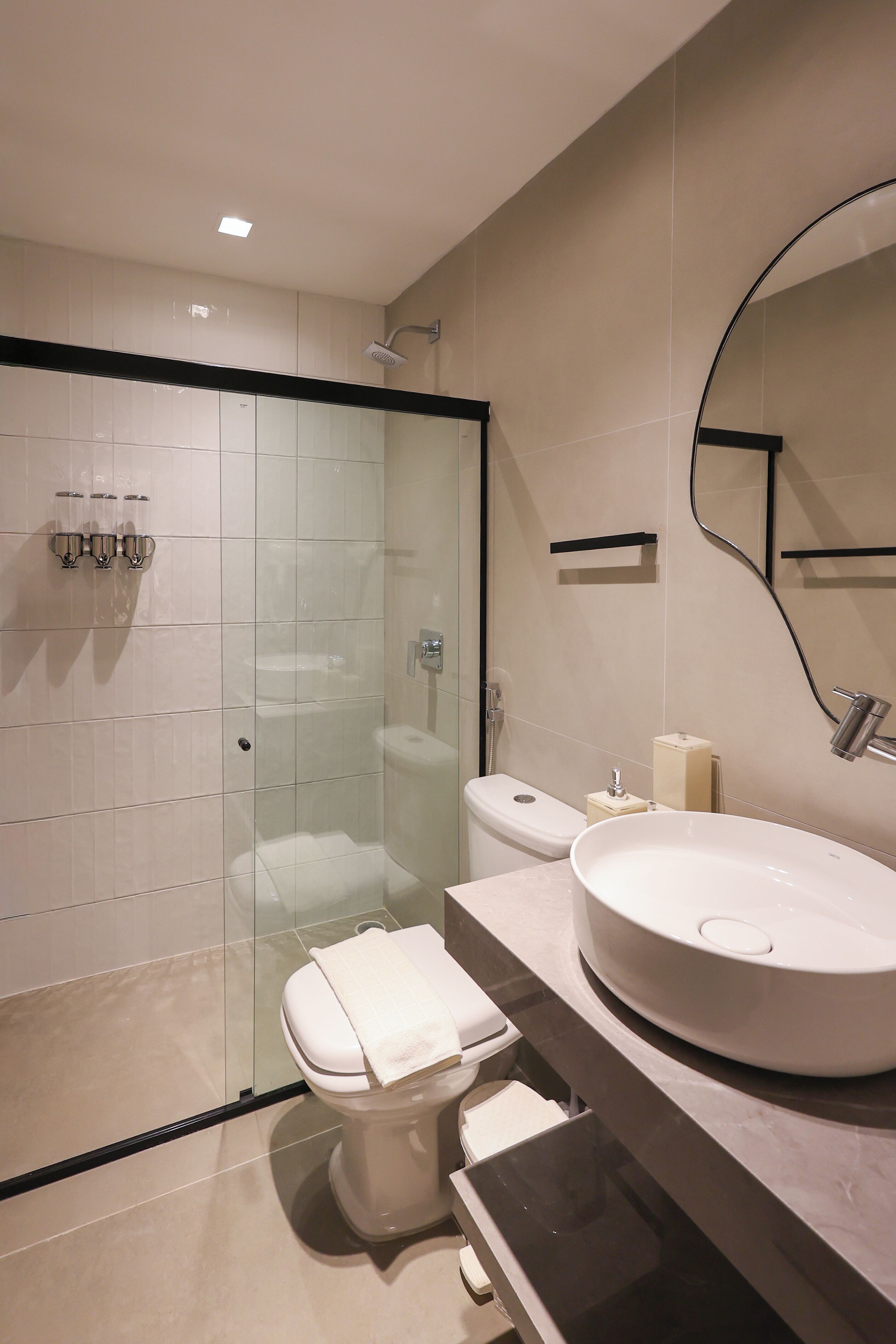 A modern bathroom with a glass-enclosed shower, a toilet, and a large sink with a mirror above it.