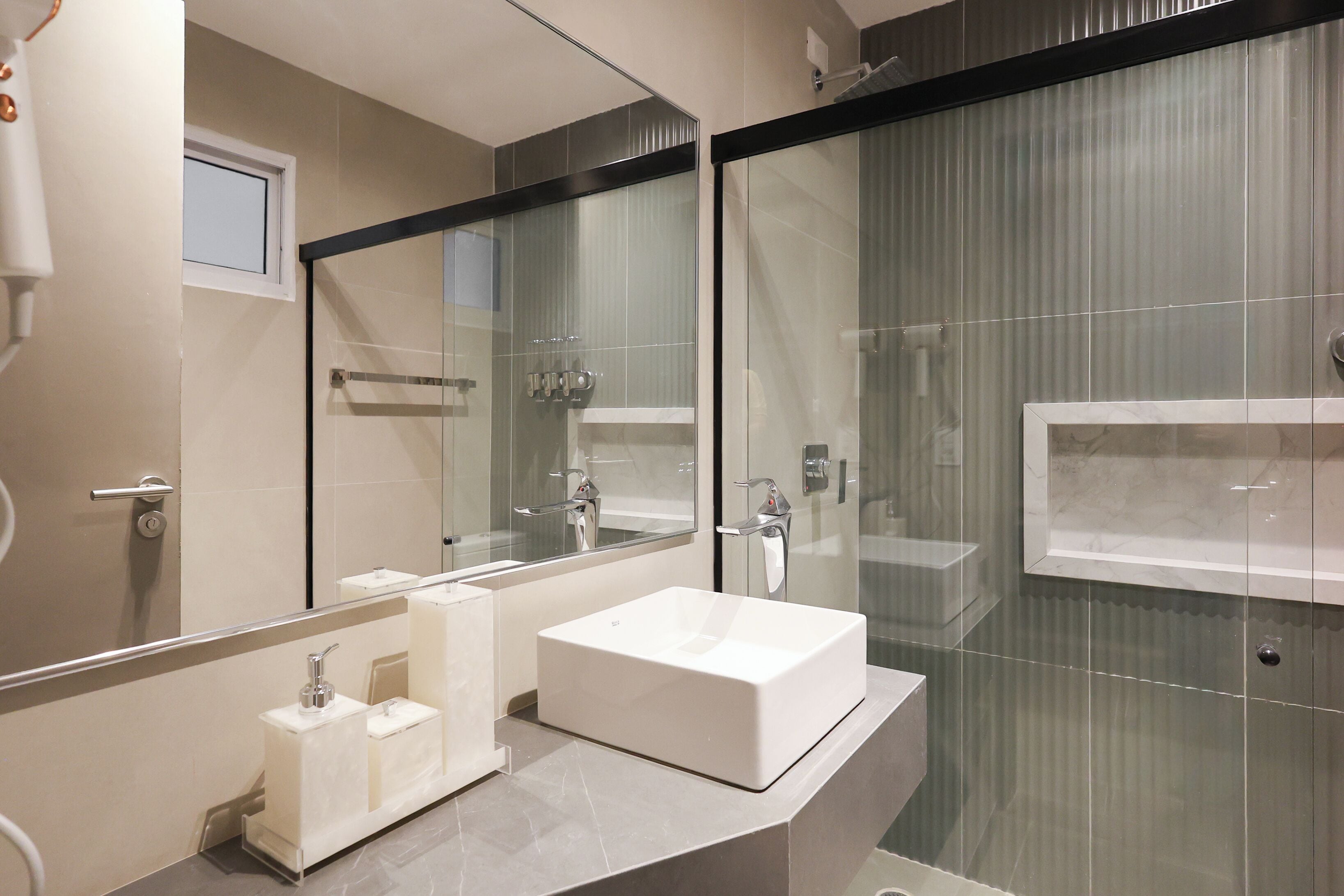 Ein modernes Badezimmer mit großem Spiegel, einem rechteckigen Waschbecken und einer Duschkabine aus Glas.