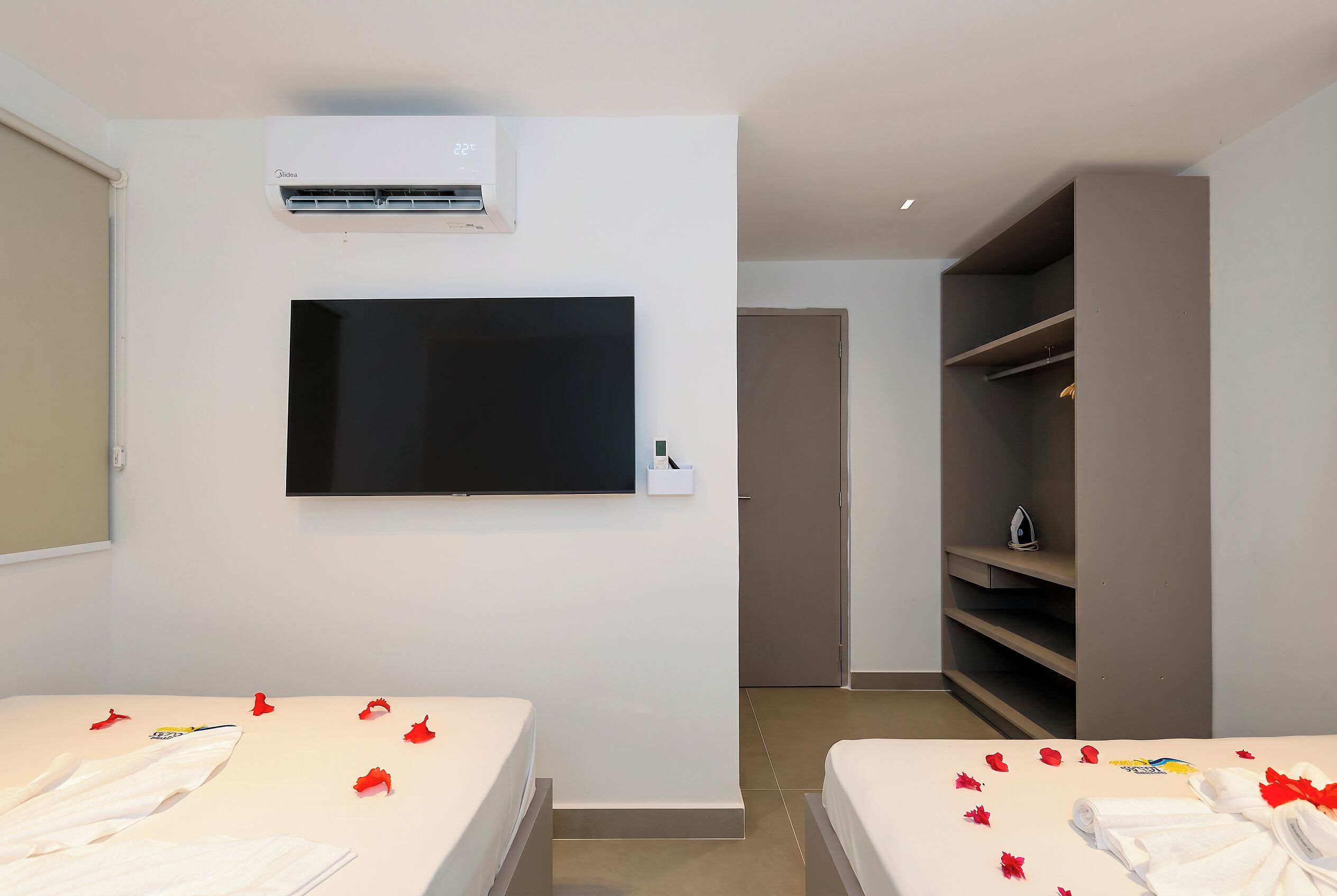 A hotel room with two beds, a TV, an air conditioner, and a wardrobe.