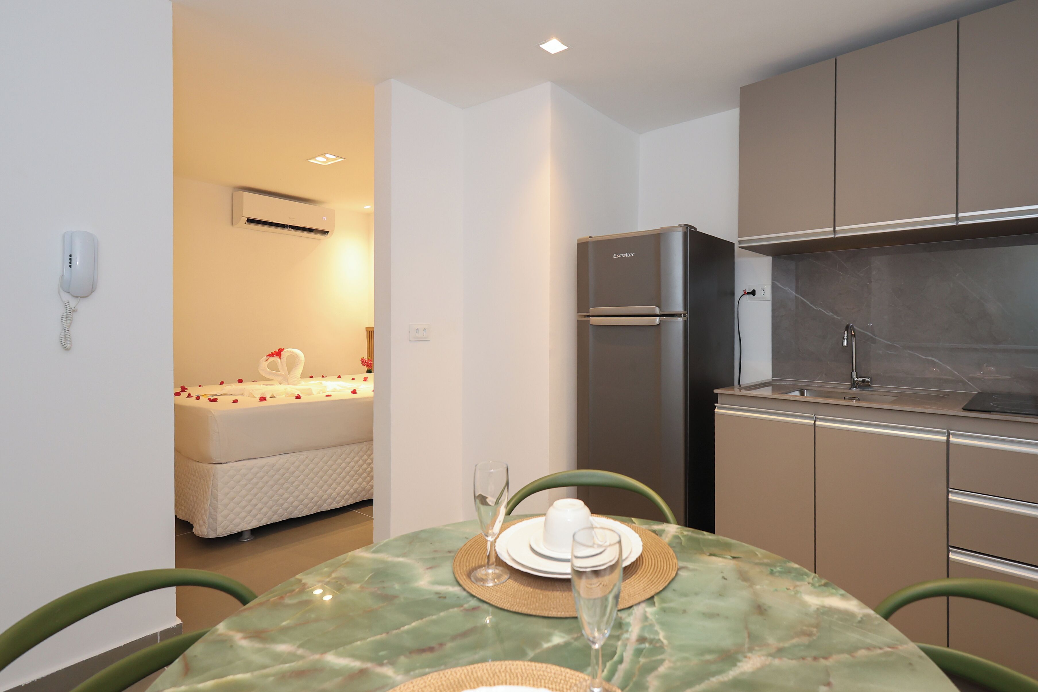 Cocina compacta con refrigerador, una mesa de comedor con sillas y una pequeña zona de preparación.