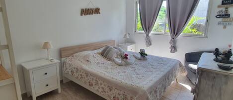 A bedroom with a bed, nightstand, dresser, and a window with curtains.
