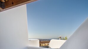 A rooftop terrace with a hot tub, white walls, and a clear view of the cityscape. - Aegean Blue Luxury Suites (Santorini)