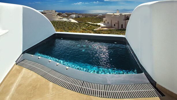 A rooftop infinity pool with a clear view of the ocean and distant buildings. - Aegean Blue Luxury Suites (Santorini)