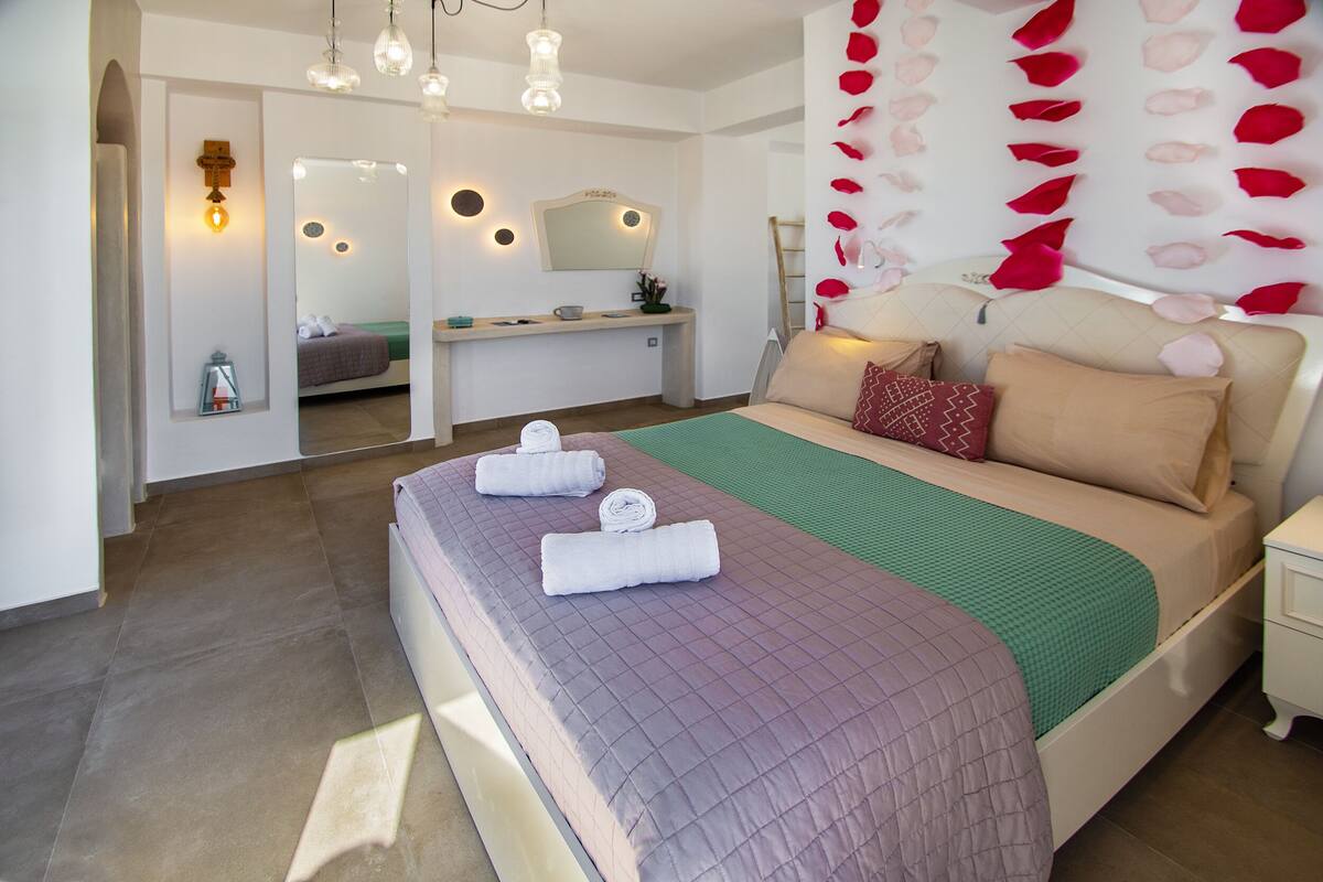 Um quarto moderno com uma cama grande, uma mesa de cabeceira, uma escrivaninha e um espelho.