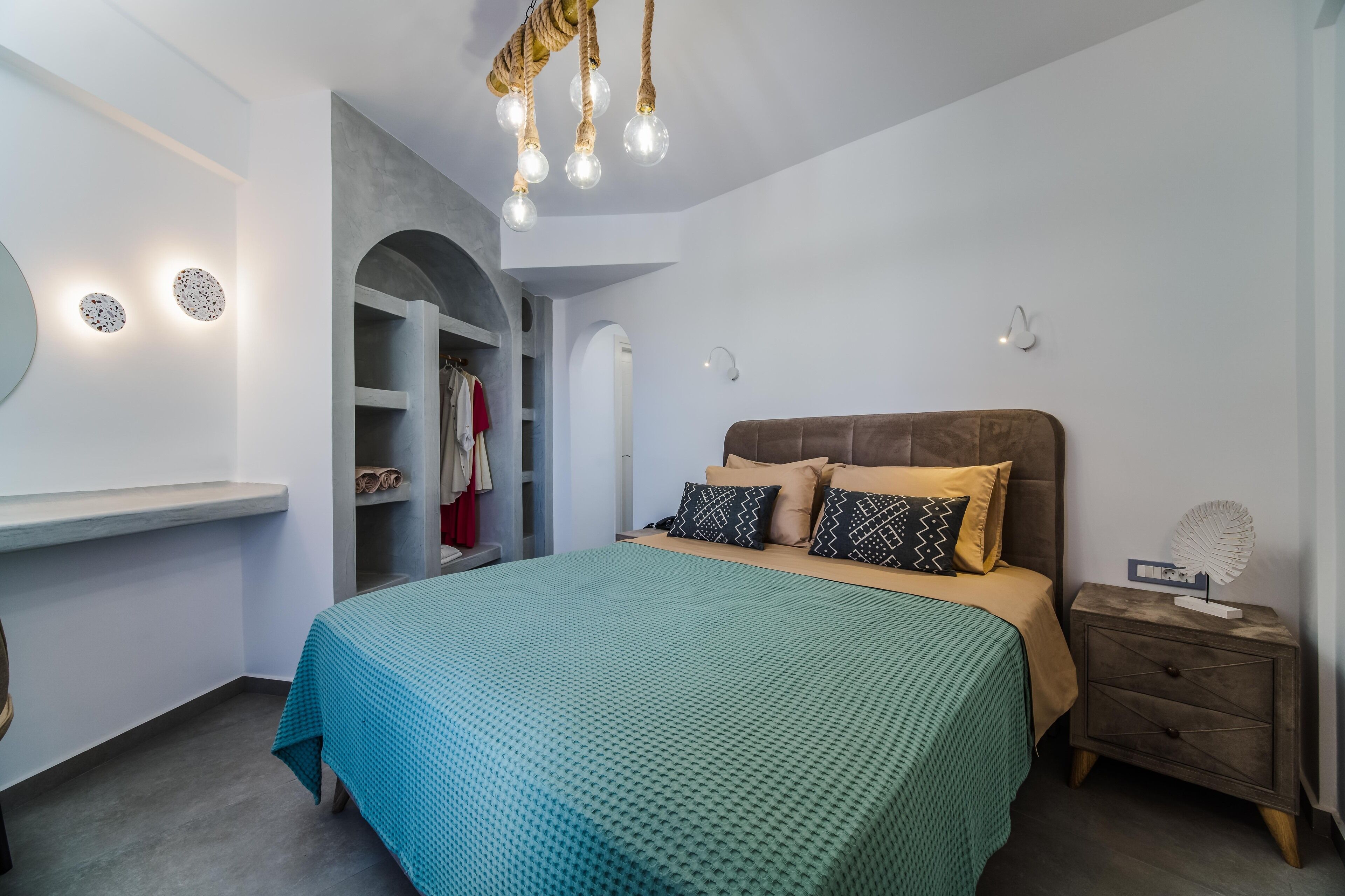 A bedroom with a bed, a nightstand, a wardrobe, and a hanging light fixture.