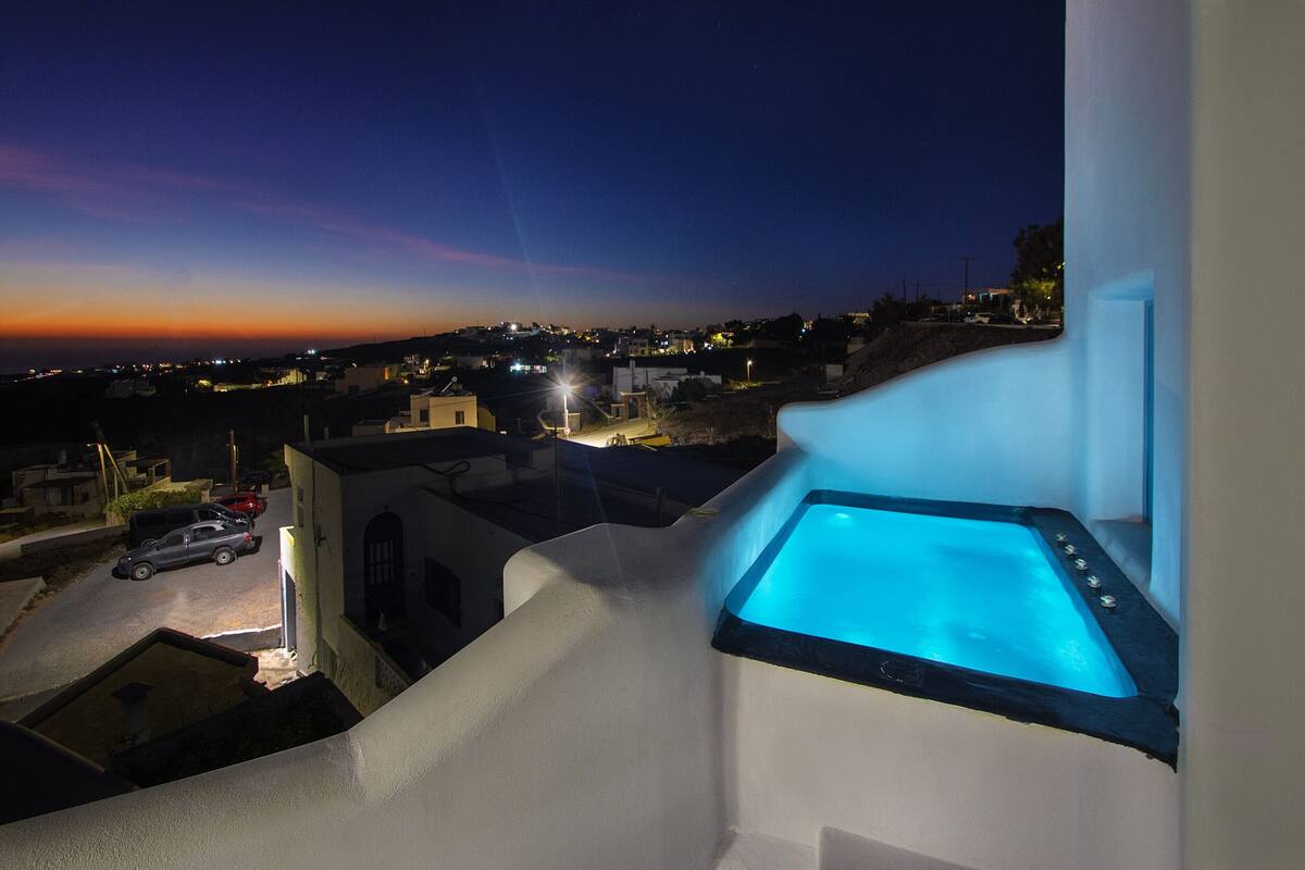 Uma varanda com banheira, com vista para uma área residencial ao entardecer.