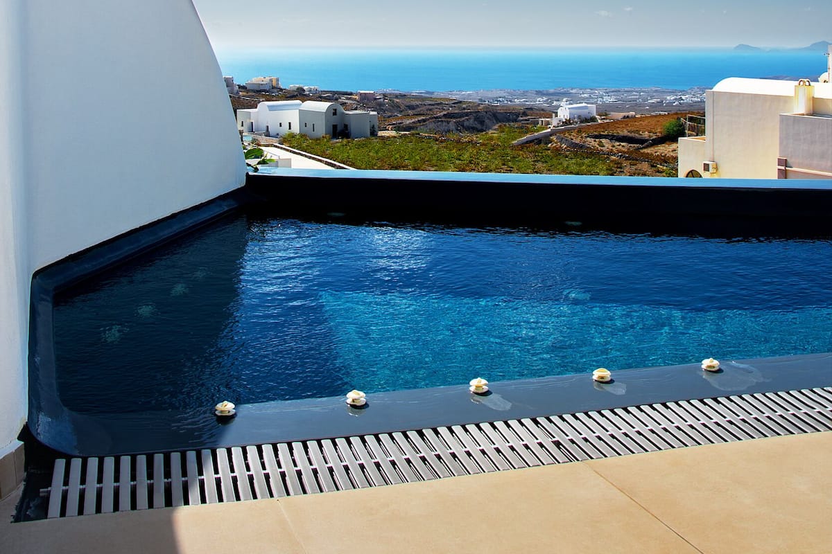 Piscina infinita no terraço com vista clara do oceano e edifícios ao longe.