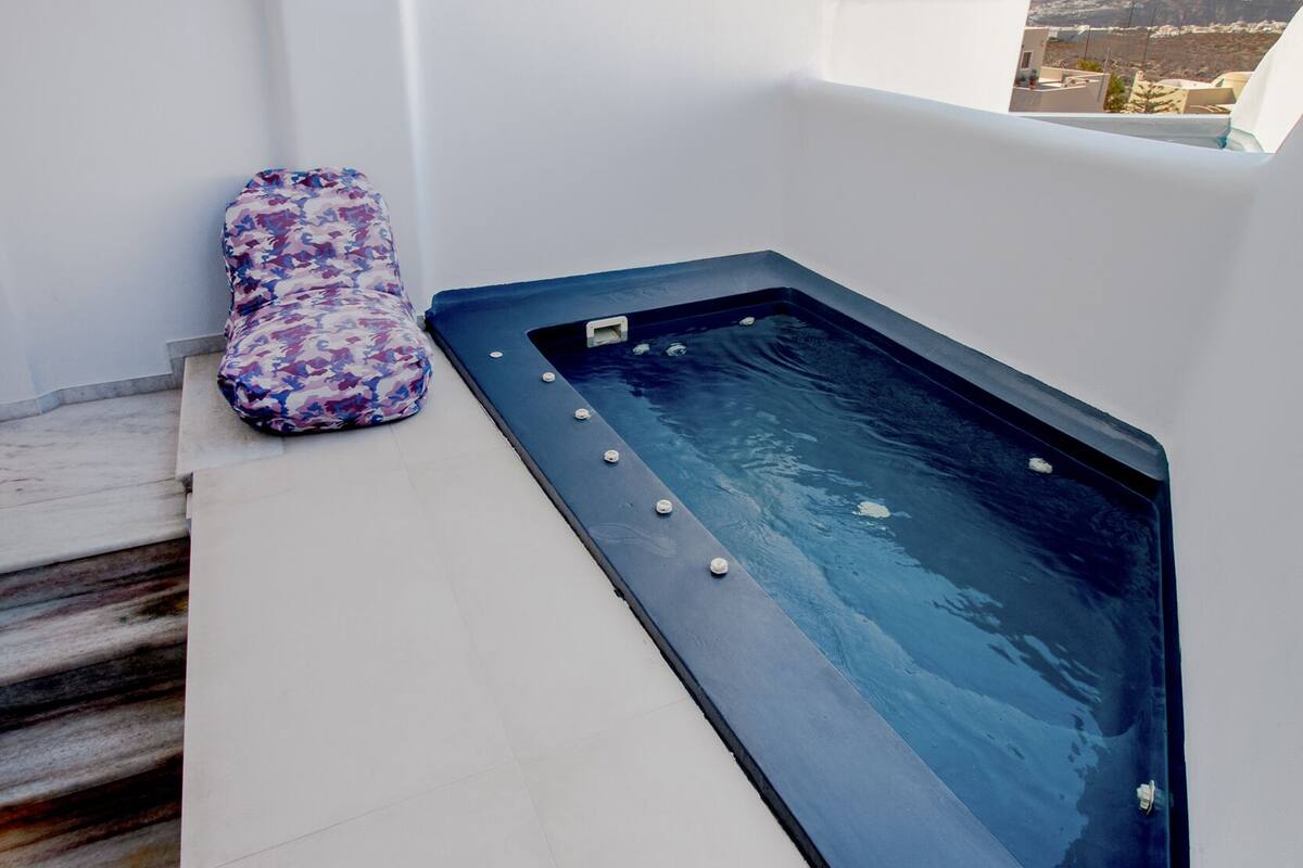 Uma área de spa com hidromassagem e um banco acolchoado, teto de madeira e vista para a cidade.
