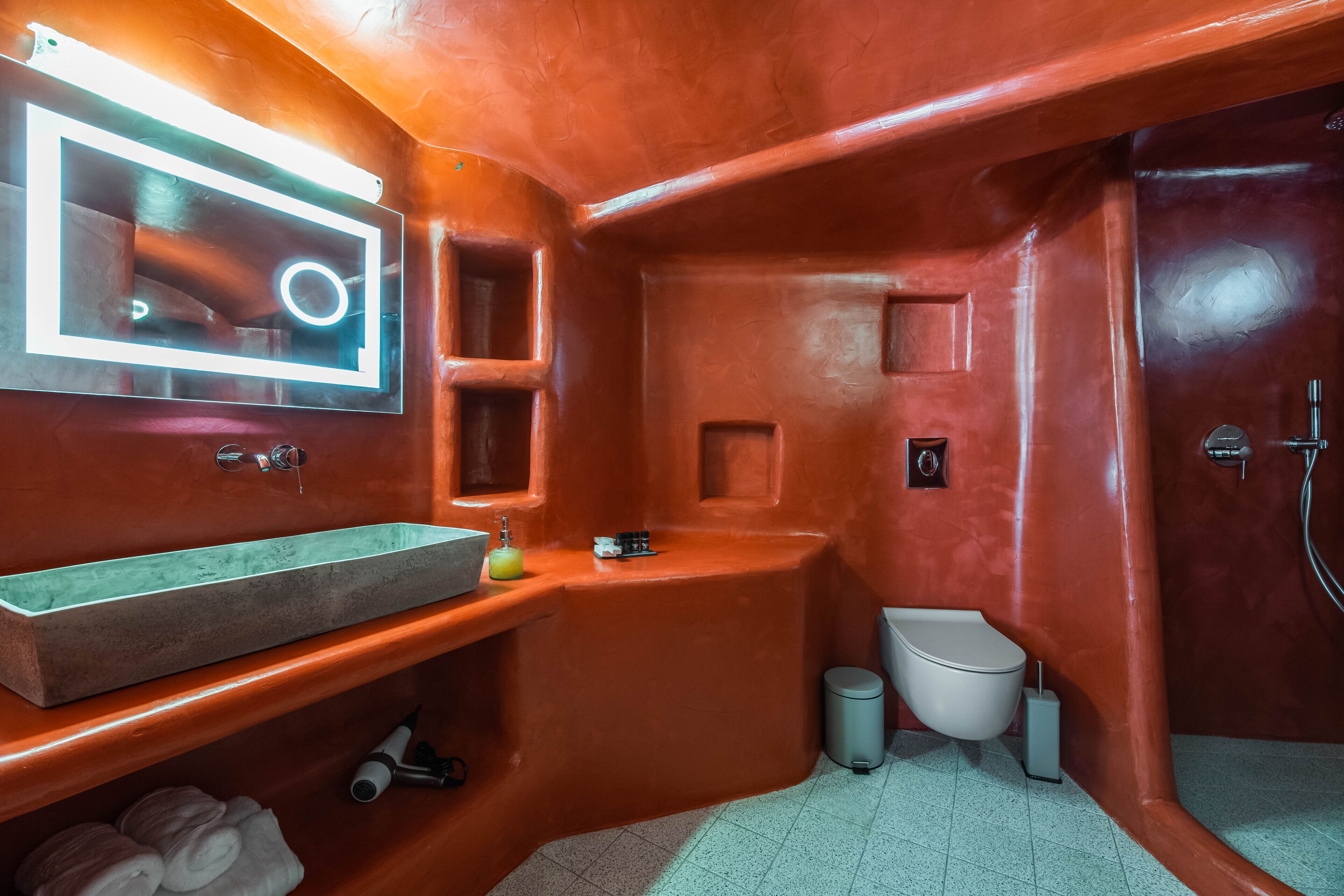 A bathroom with a large mirror, a sink, a toilet, and a shower area.