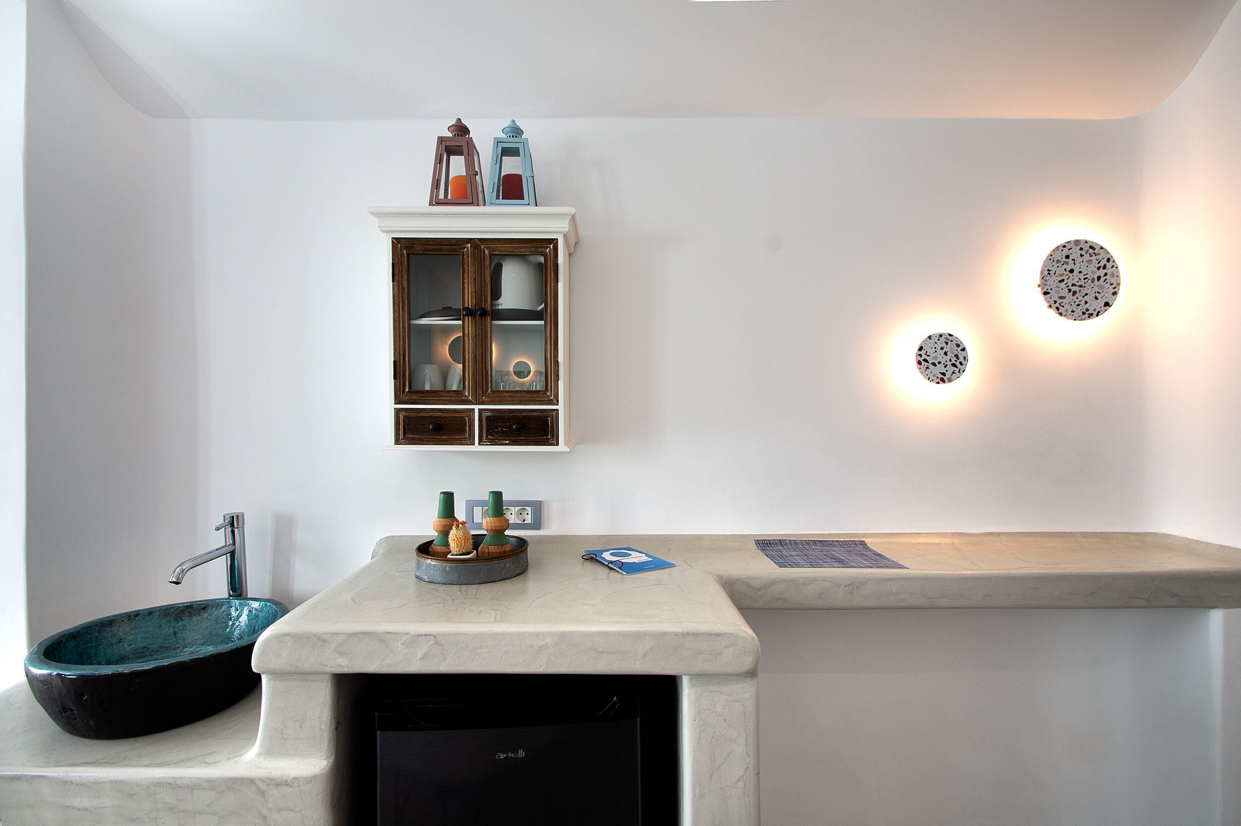Une salle de bain moderne avec un lavabo sur pied, un meuble avec des portes en verre et des appliques murales.