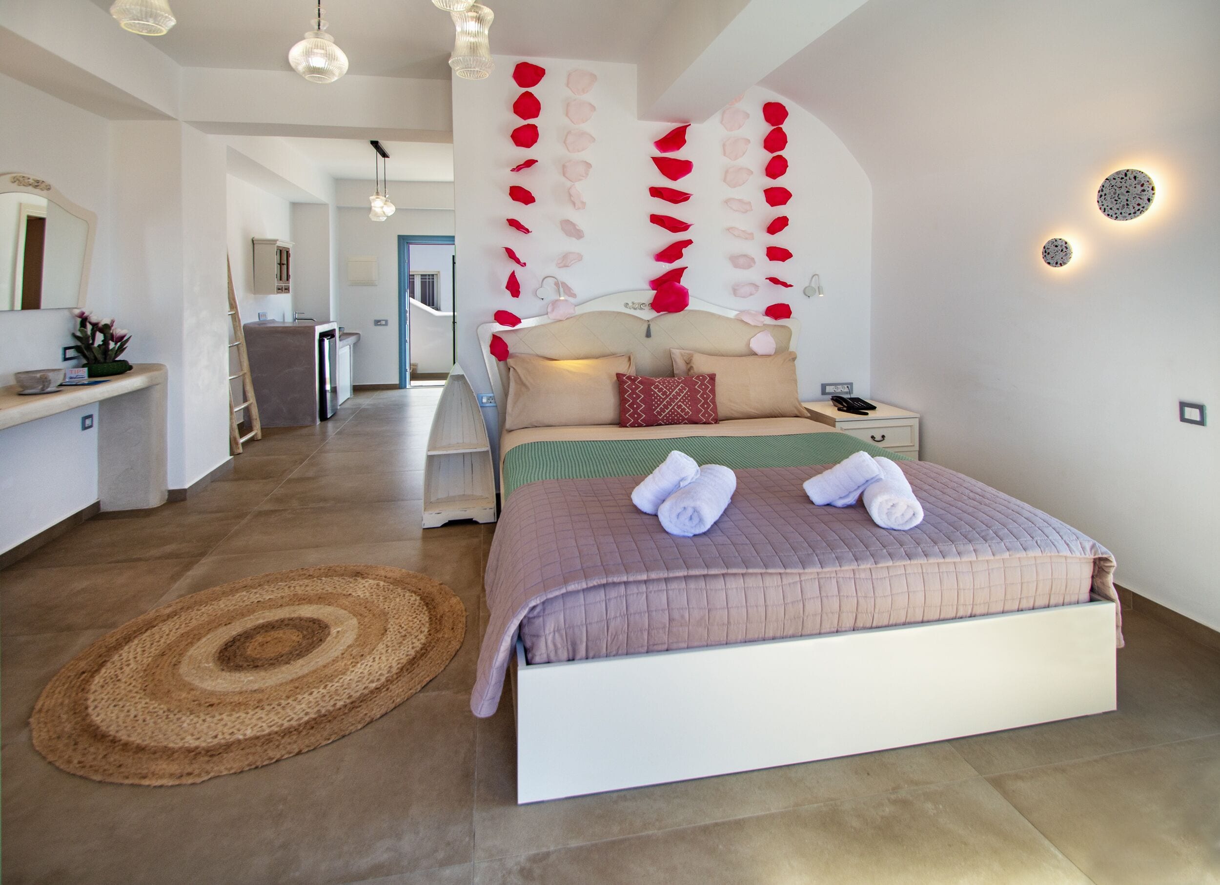 Une chambre moderne avec un grand lit, une table de chevet, une commode, un miroir et un mur agrémenté d’éléments décoratifs.