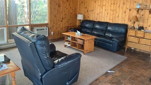 A wooden-paneled room with a leather sofa, a wooden coffee table, and a lamp.