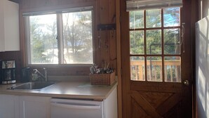A kitchen with a wooden door, a window, and a sink.