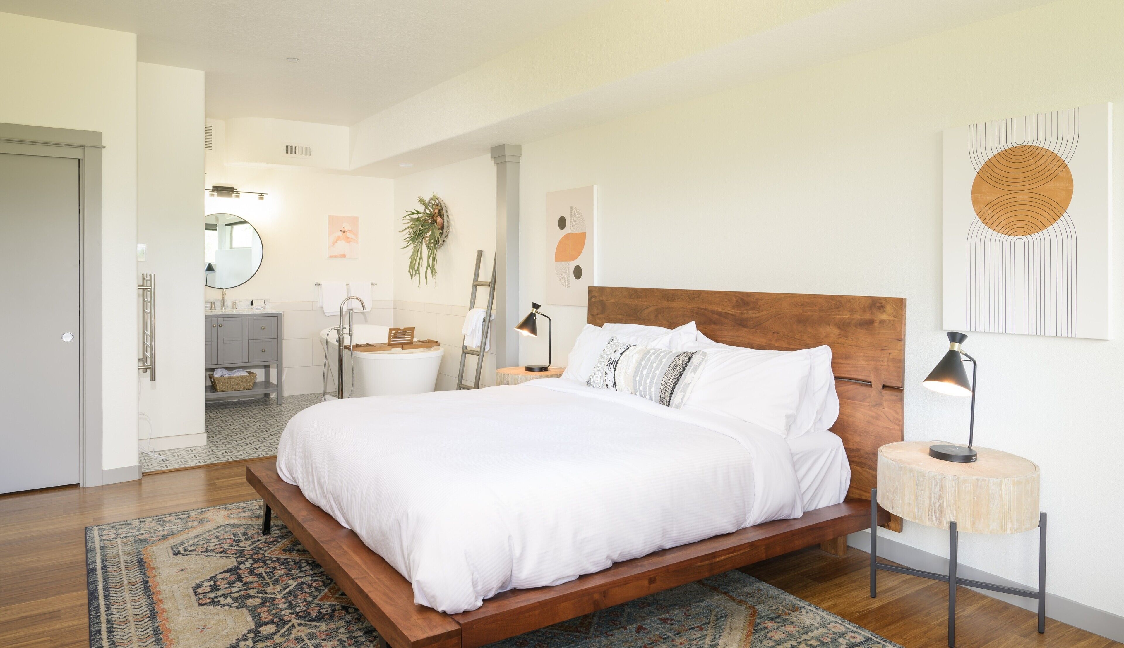 Una camera da letto moderna con un letto in legno, un comodino, uno specchio e un bagno sullo sfondo.
