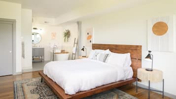 Una camera da letto moderna con un letto in legno, un comodino, uno specchio e un bagno sullo sfondo.
