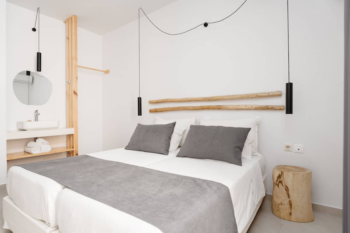 Een moderne slaapkamer met een bed, nachtkastje en een ronde spiegel.