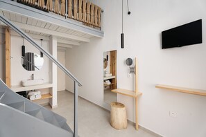 Een moderne badkamer met een houten wastafelmeubel, een ronde spiegel, een handdoekrek en een toilet.
