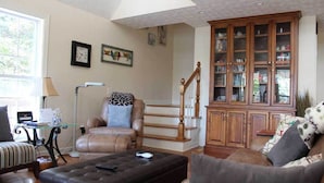 Un salon spacieux avec un canapé en cuir, une table basse, une cheminée et un escalier en bois.