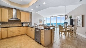 A spacious kitchen with a large island, wooden cabinets, and a dishwasher.