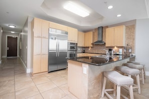 A modern kitchen with stainless steel appliances, wooden cabinets, and a central island with bar stools.