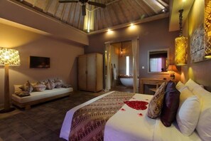 Une chambre à coucher avec un lit, une table de chevet, une lampe et une vue sur la salle de bain.