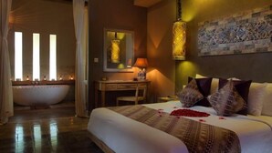 Ein Hotelzimmer mit einem großen Bett, einem Schreibtisch, einer Badewanne und einer Wand mit Dekorationen.