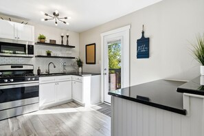 A modern kitchen with white cabinetry, a black countertop, and a stainless steel stove.
