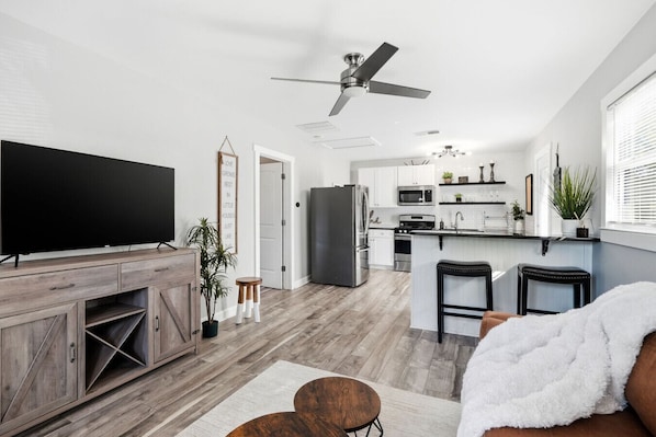 A modern kitchen with white cabinets, a stainless steel refrigerator, and a microwave.
