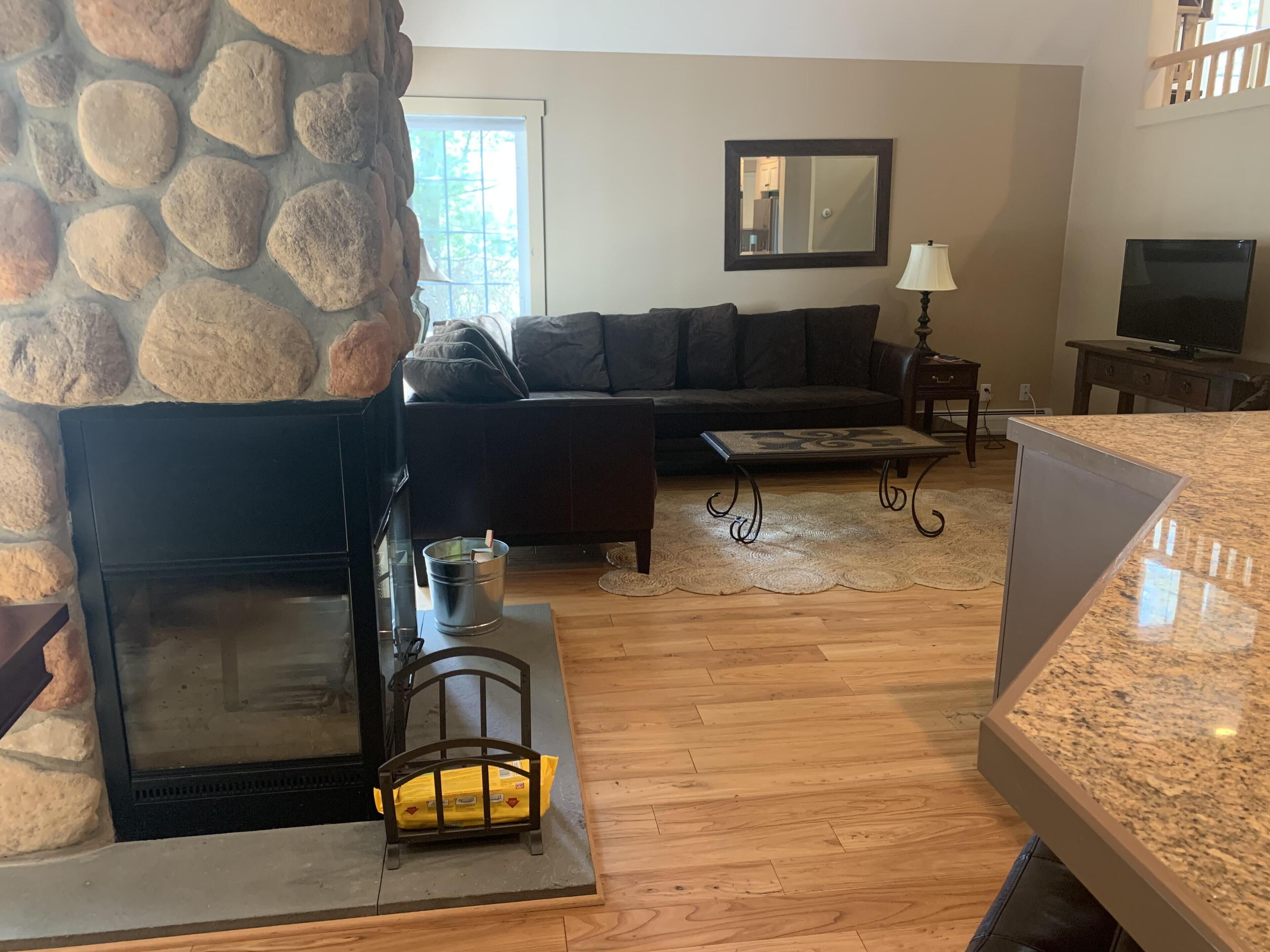 A living room with a stone fireplace, a sofa, a coffee table, and a television.