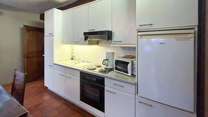 Eine kompakte Küche mit weißen Schränken, einem eingebauten Geschirrspüler, einer Mikrowelle und einem Kühlschrank.