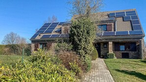 Ein Haus mit Solaranlage auf dem Dach und einer gepflasterten Auffahrt zum Eingang.