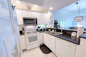 Kitchen features a window with an outside view, black countertop, and stainless steel appliances.
