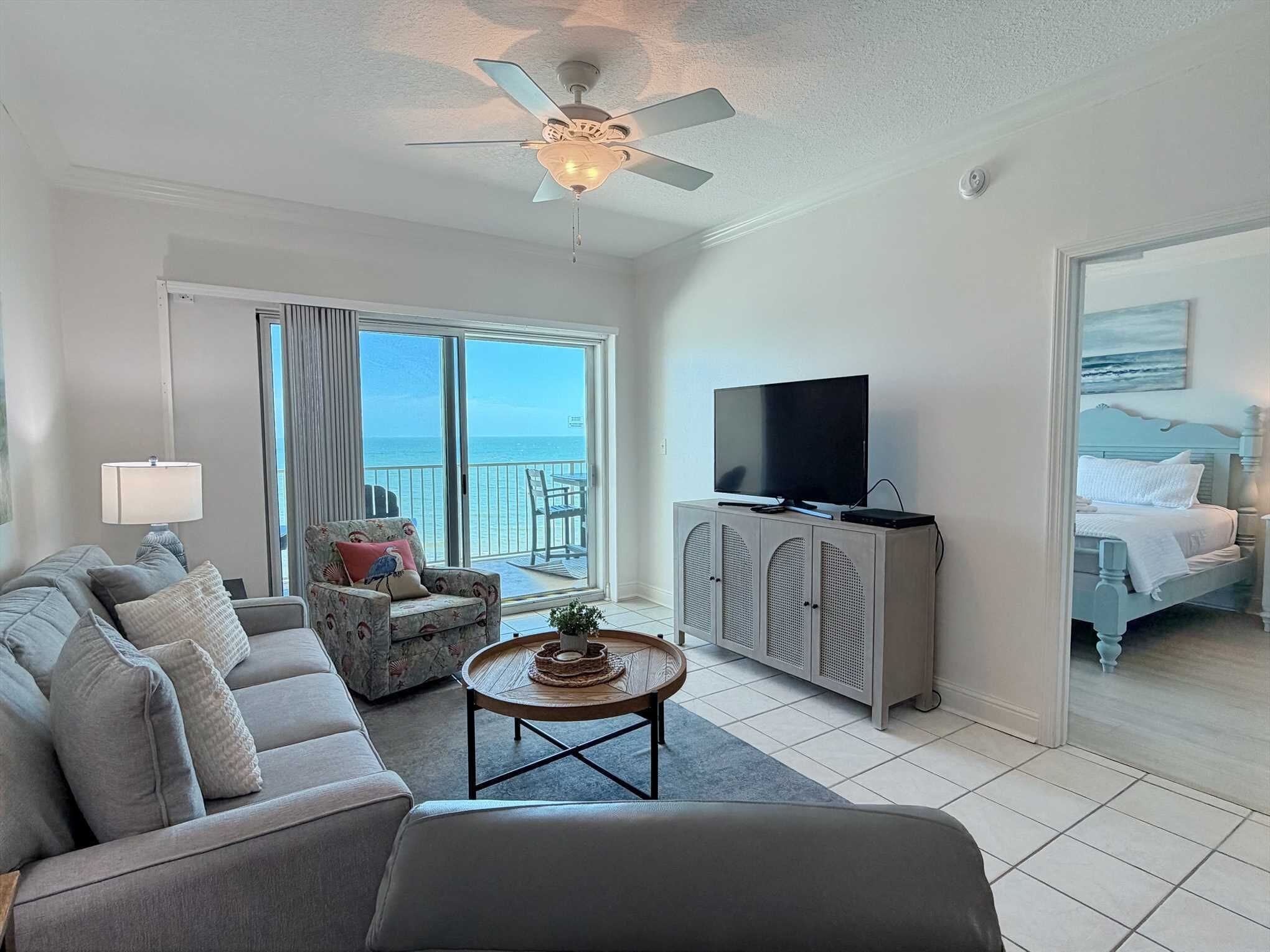 A hotel room with a balcony, a sofa, a television, and a bed.