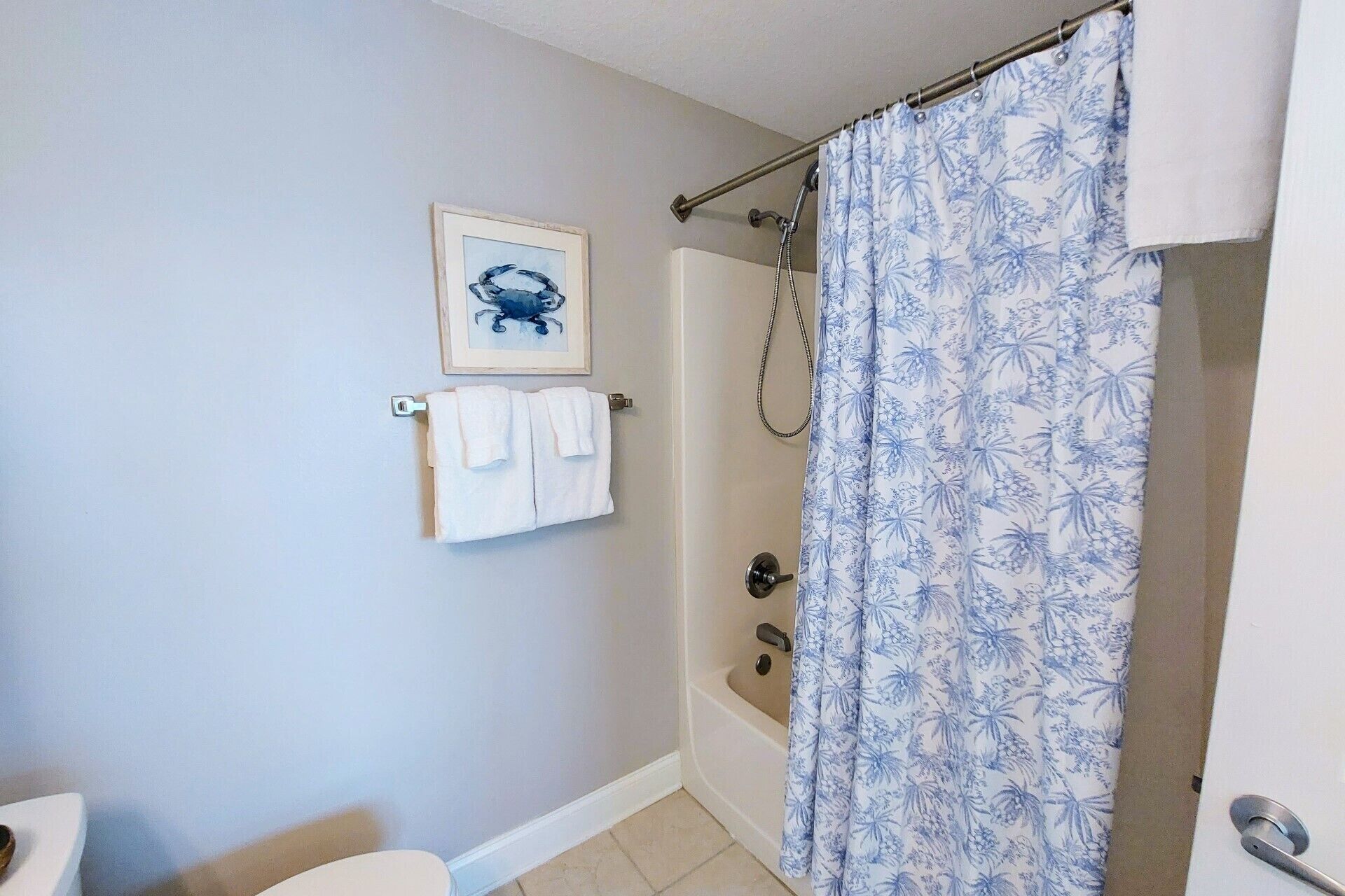Une salle de bain avec un rideau de douche, un tableau encadré et un porte-serviettes.