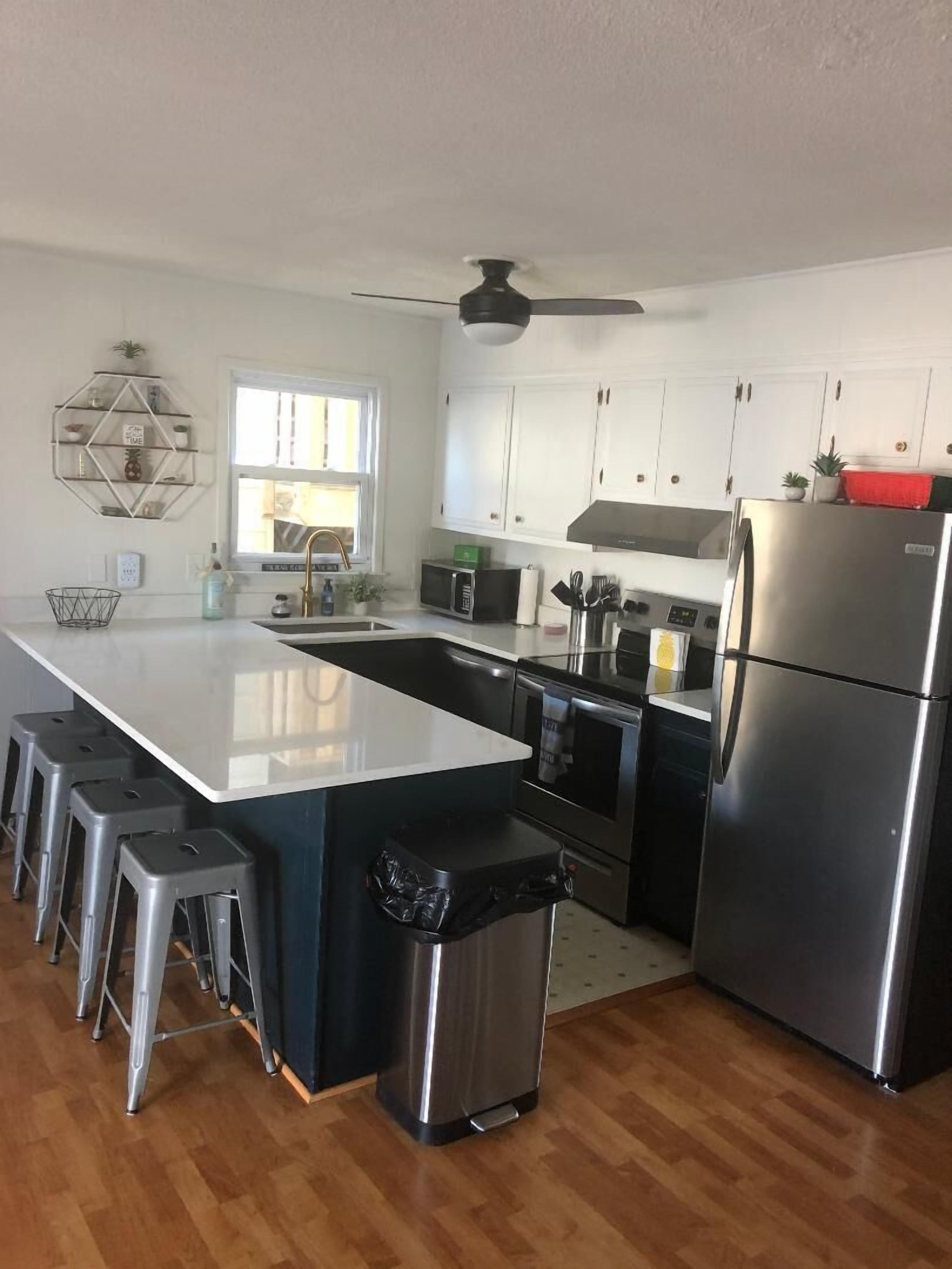 A modern kitchen with a central island, stainless steel appliances, and a ceiling fan.