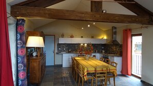 A kitchen with a dining area, featuring a tiled floor, wooden beams, and a tiled backsplash. - Gite de Chapelèche les Glycines Pour 8 à 10 Personnes (Gluiras)