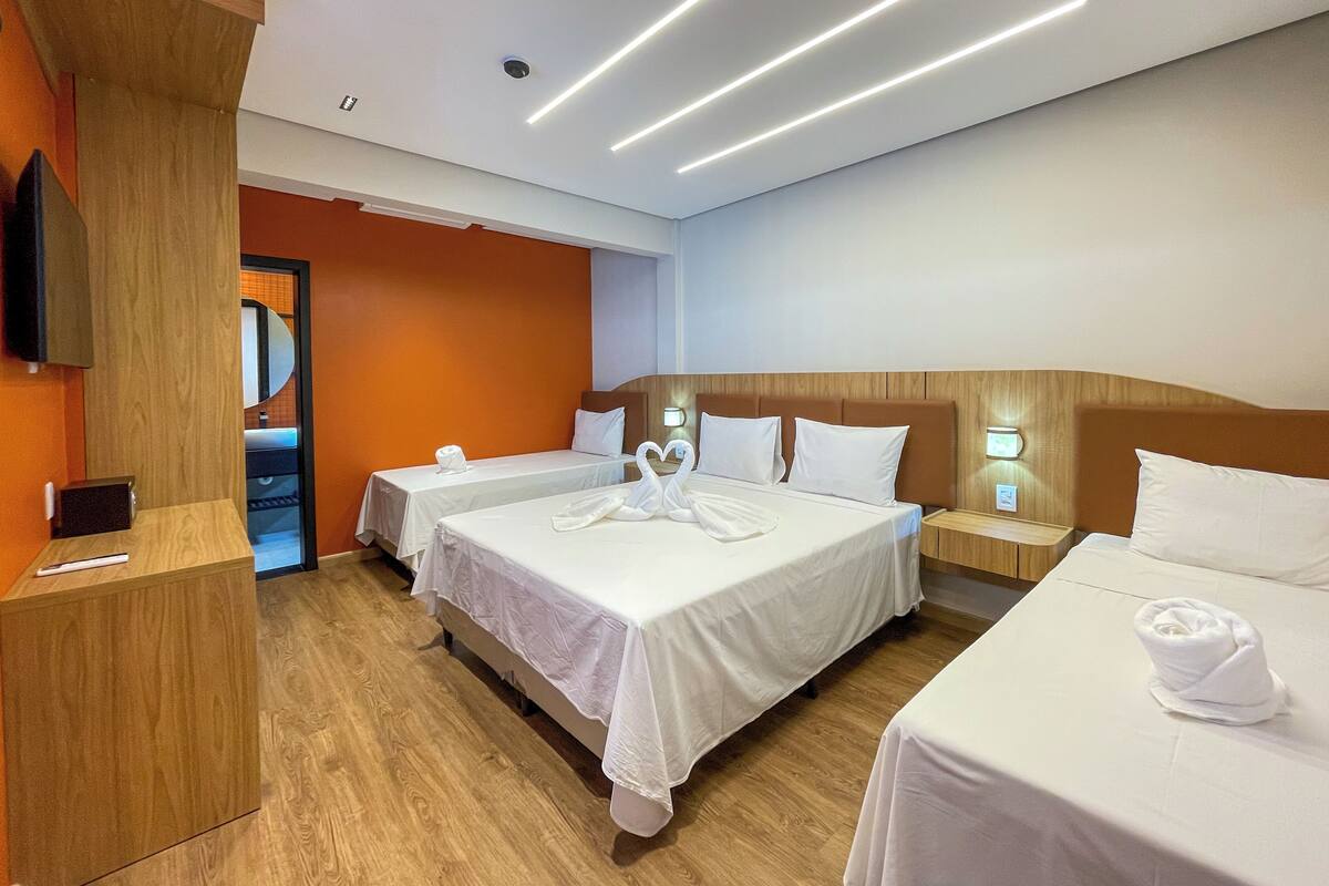 Ein Hotelzimmer mit zwei Betten, einem Holzkopfstück, einem Schreibtisch aus Holz und einem Flachbildfernseher.
