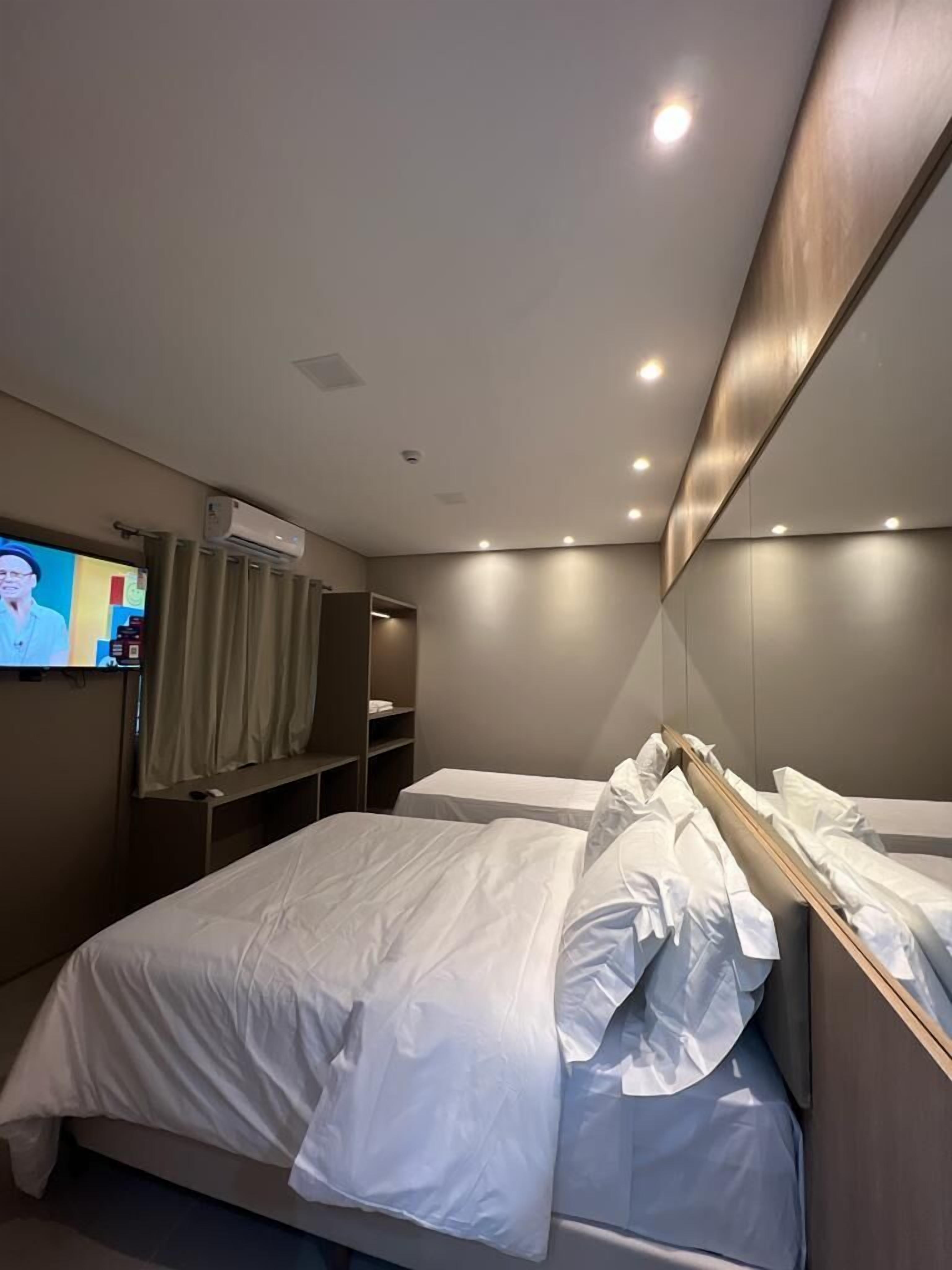 A hotel room with a bed, a television on the wall, and a mirror.
